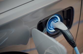 Coche eléctrico enchufado a un cargador bajo el sol de verano