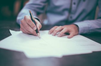 Persona firmando un contrato de seguro sobre una mesa