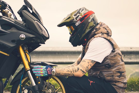 Motorista con casco y chaqueta circulando de día, guantes y calzado obligatorios