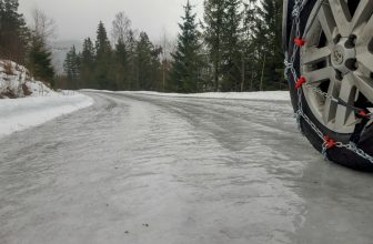 Rueda de coche con cadenas de nieve montadas sobre carretera nevada